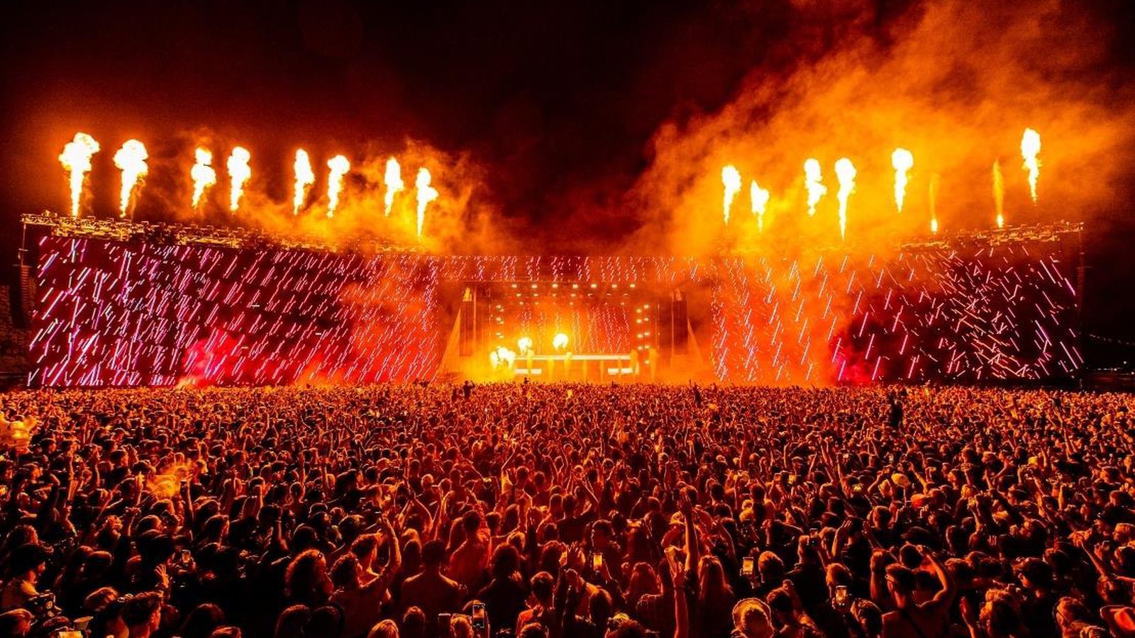 Pyrotechnics firing across the Creamfields main stage above a full festival crowd.